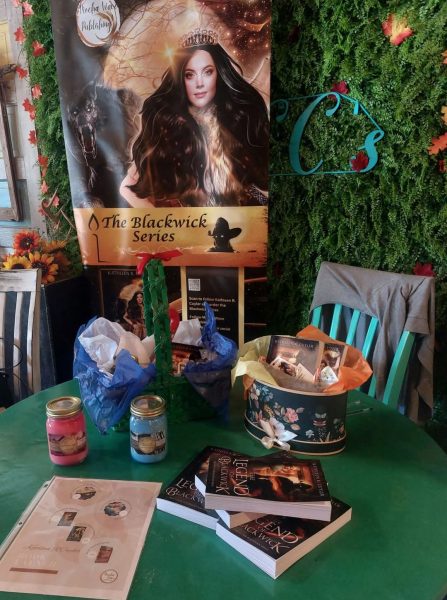 A table setup at CC's coffee shop with books, candles, and greenery for *The Legend of Blackwick* launch